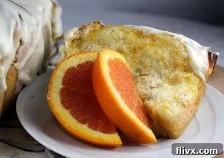 A golden-brown slice of Orange Pull-Apart Coffee Cake on a white plate, garnished with fresh orange slices, ready to be enjoyed.