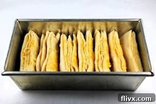 Orange Pull Apart Bread baking in a metal loaf pan, showcasing its layered structure.