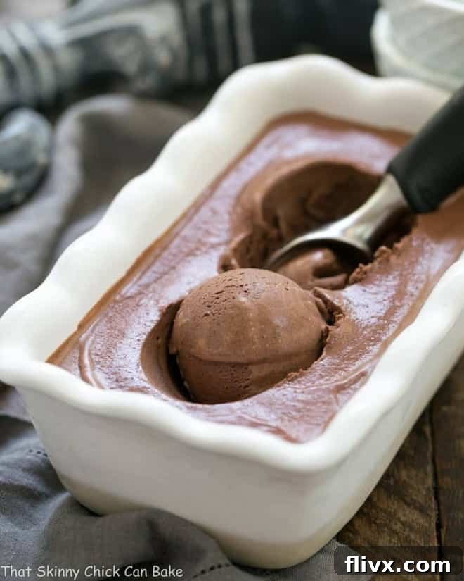 Chocolate Ice Cream with Fudge Sauce in a freezer dish with an ice cream scoop, showcasing its rich, dark color and smooth texture, ready to be served.