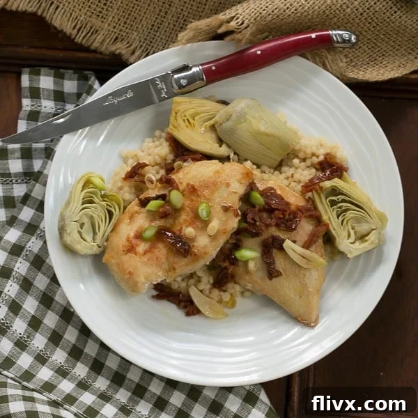 Overhead view of a delicious plate of Chicken with artichokes and sundried tomatoes served with Israeli couscous