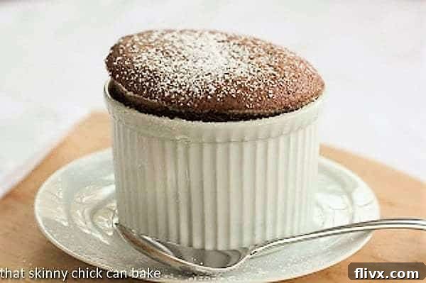 A perfectly risen individual chocolate soufflé in a pristine white ramekin, lightly dusted with powdered sugar.