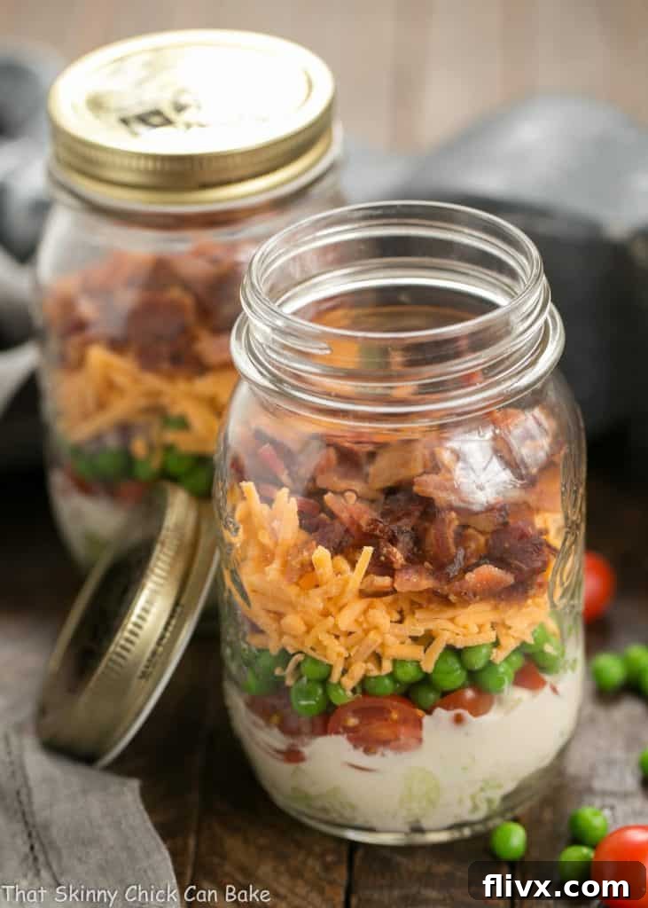 Two Make Ahead 7-Layer Salads in a Jar, one with the lid off, ready for meal prep