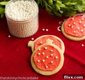 Delicious frosted sugar cookies adorned with colorful sprinkles, resting on a vibrant red napkin.