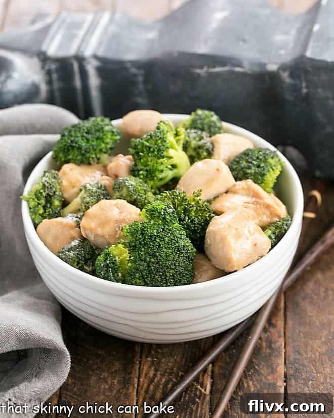 Close-up view of chicken and broccoli stir fry in a white bowl, showing tender chicken pieces and bright green broccoli florets.
