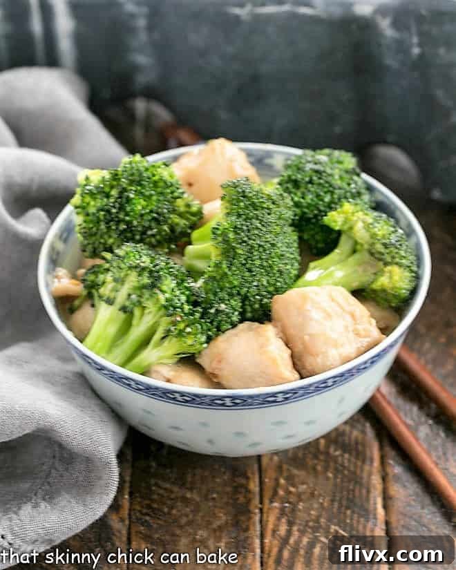 Chicken and broccoli stir fry in a blue and white ceramic bowl, garnished with green onions.