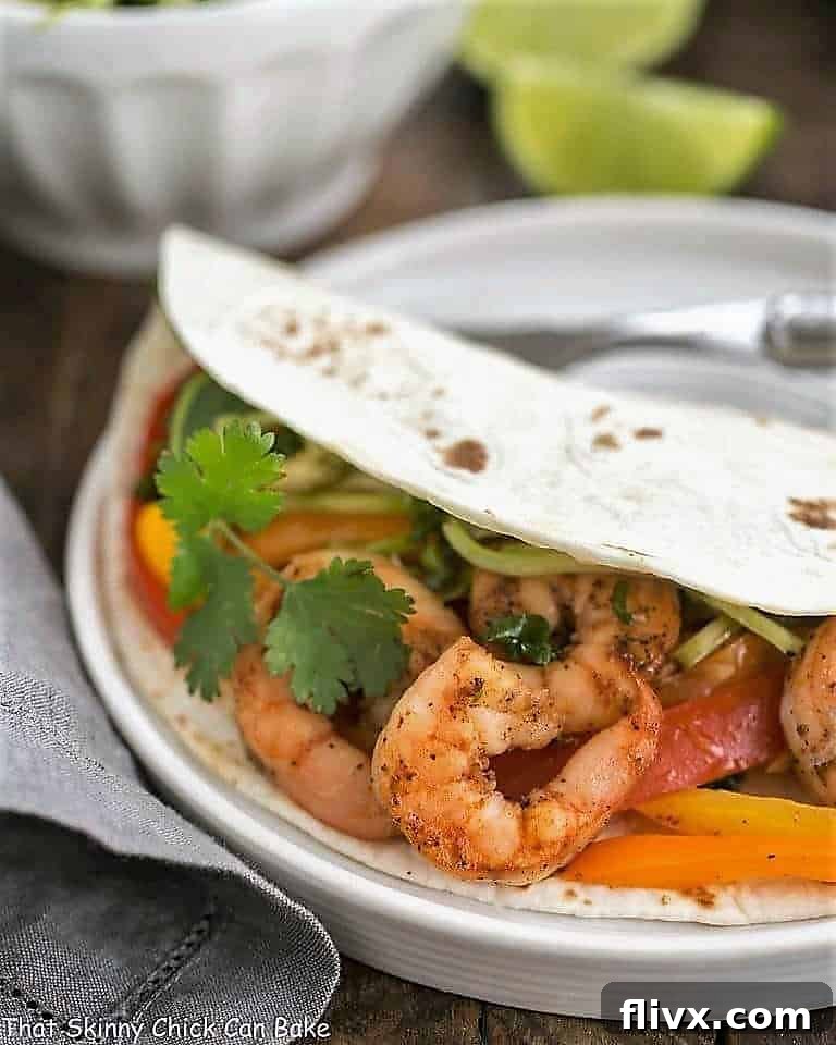 A close-up of a Spicy Shrimp Fajita filling artfully arranged in a warm tortilla, garnished with fresh cilantro.