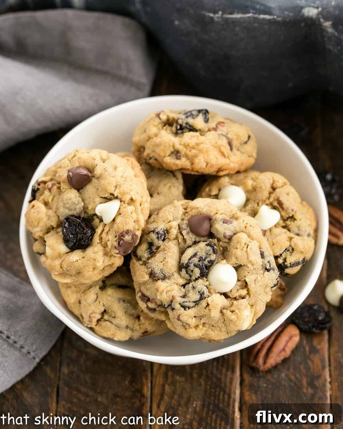 Close-up overhead view of a ceramic bowl brimming with homemade oatmeal cherry chocolate chip cookies, showcasing their golden-brown edges and soft centers.