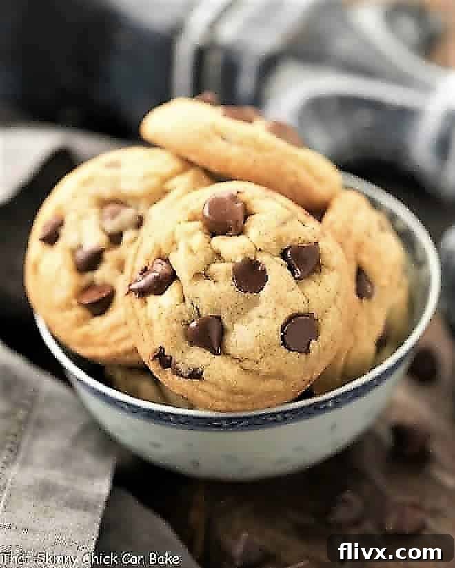 A bowl overflowing with freshly baked Double Chocolate Chip Cookies, featuring both milk and semi-sweet chocolate chips, set against a rustic blue and white background.