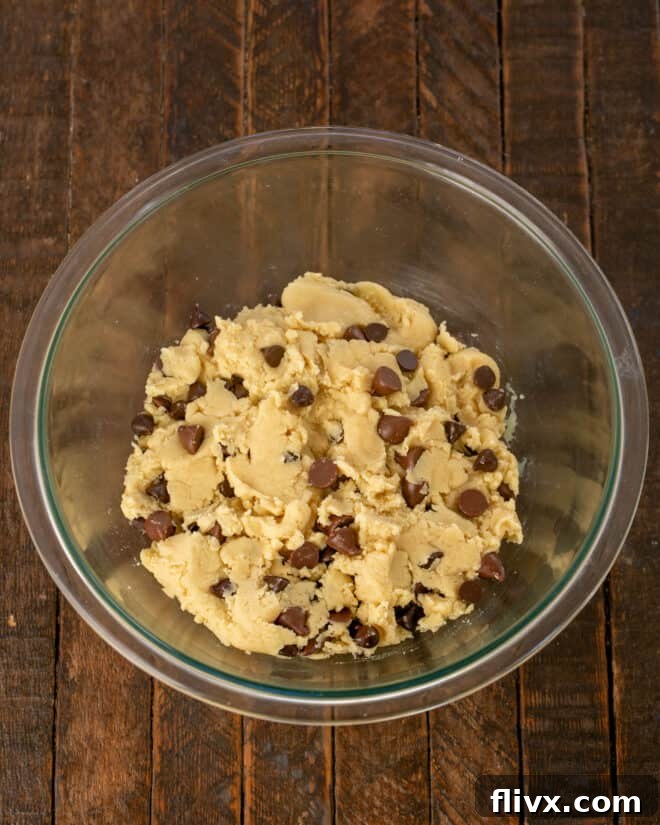 Step 3: A generous amount of mixed chocolate chips (semisweet and milk chocolate) are folded into the cookie dough, followed by chilling the dough to develop flavors and prevent spreading.