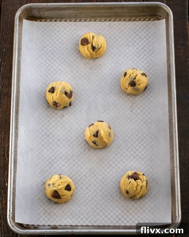 Step 4: Uniform balls of chilled cookie dough are neatly scooped and placed onto a parchment-lined baking sheet, spaced appropriately for baking.