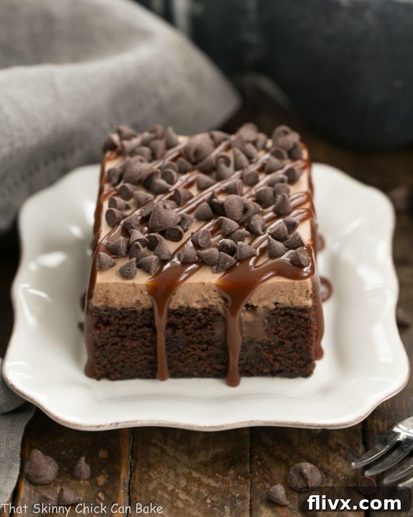 A slice of rich Chocolate Kahlua Poke Cake served on a small white plate, showcasing its moist texture and creamy topping.