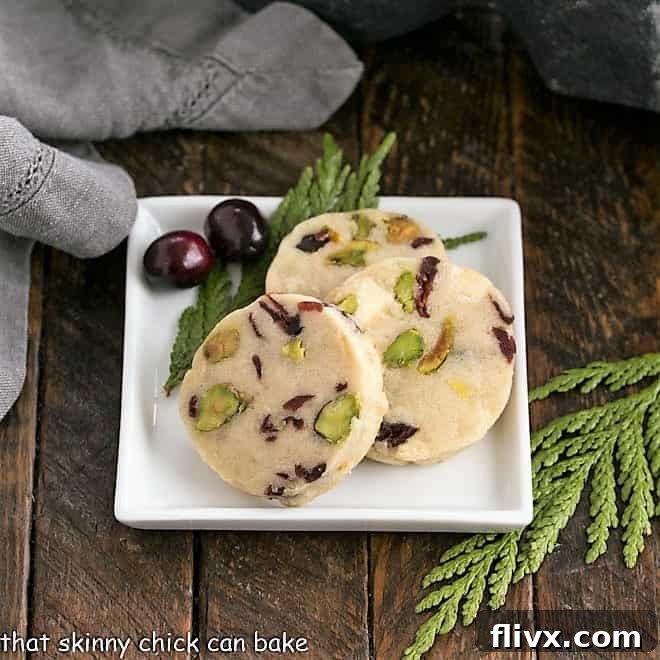 Close-up of baked Cranberry Pistachio White Chocolate Shortbread cookies arranged on a square white plate, highlighting their vibrant colors.