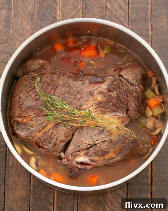 Step 5: Returning the seared chuck roast to the Dutch oven with the liquids and herbs, bringing it to a simmer before covering and slow cooking.