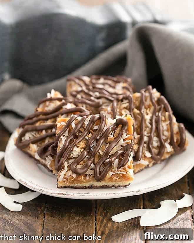 Homemade samoa bars arranged artfully on a round plate, garnished with scattered shreds of toasted coconut, emphasizing their delicious texture.