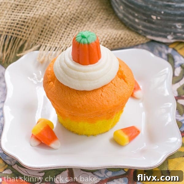 Candy Corn Cupcakes for Halloween on a square white plate, showing the yellow and orange layers with white frosting