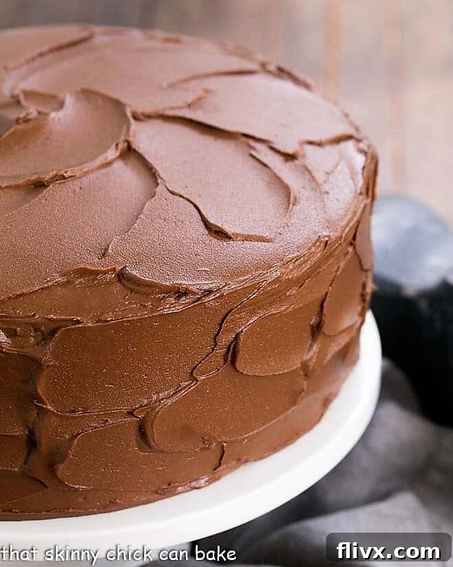 Decadent Chocolate Layer Cake with White Chocolate Ganache, perfectly sliced on a white cake stand.