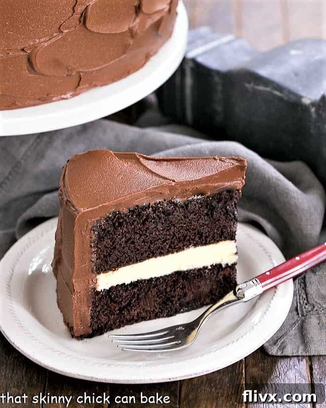 A slice of Chocolate Layer Cake with a thick layer of White Chocolate Ganache on a dessert plate.