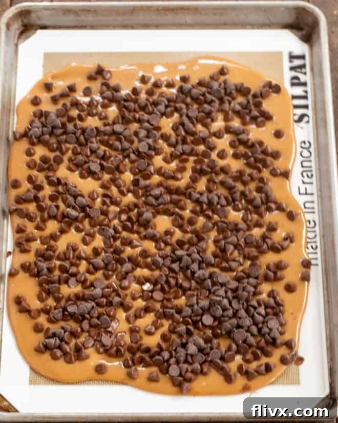 The initial toffee base being spread thinly onto a baking sheet, ready for chocolate.