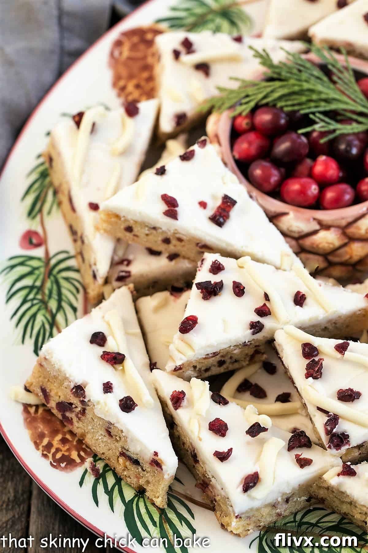A festive tray overflowing with starbucks cranberry bliss bars, accompanied by a small bowl of fresh cranberries for garnish.