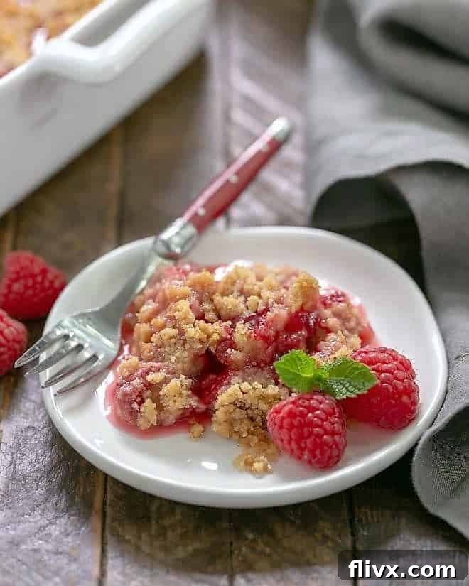 Fresh Raspberry Crisp portion on a small white plate garnished with fresh raspberries and mint.