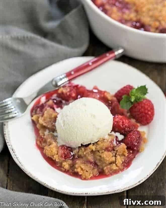 Overhead view of Fresh Raspberry Crisp on a white dessert plate with vanilla ice cream and fresh berries.