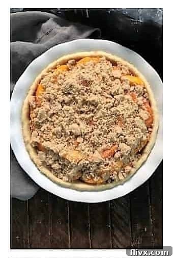 Step 4: The remaining, larger crumb topping pieces are sprinkled generously over the peach filling.