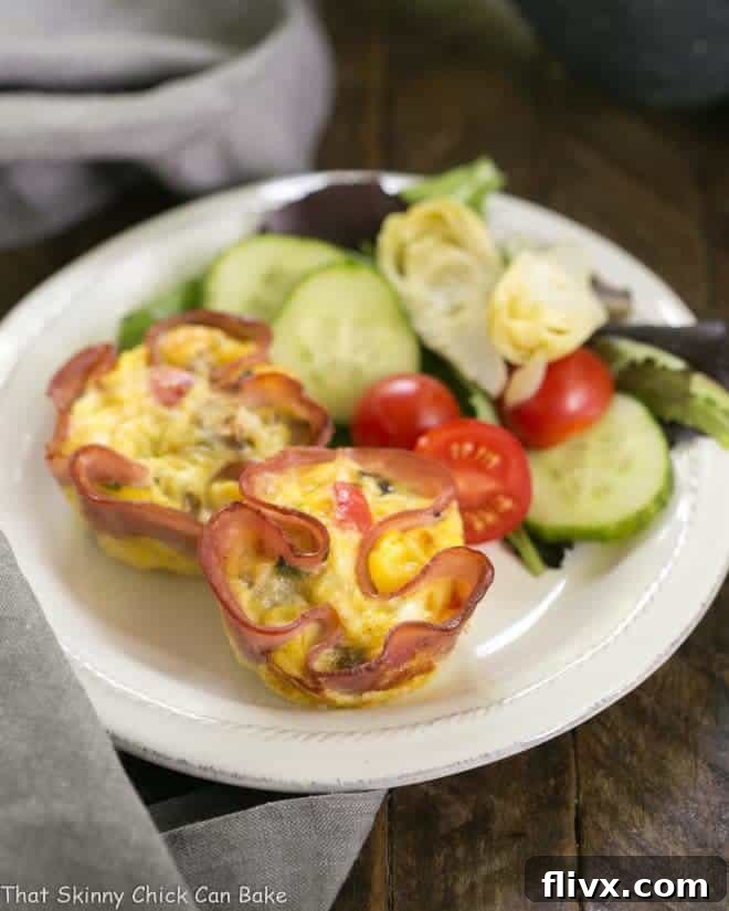 Delicious Egg Muffins in Ham Cups served alongside a fresh green salad on a small white plate, perfect for a light and healthy meal.