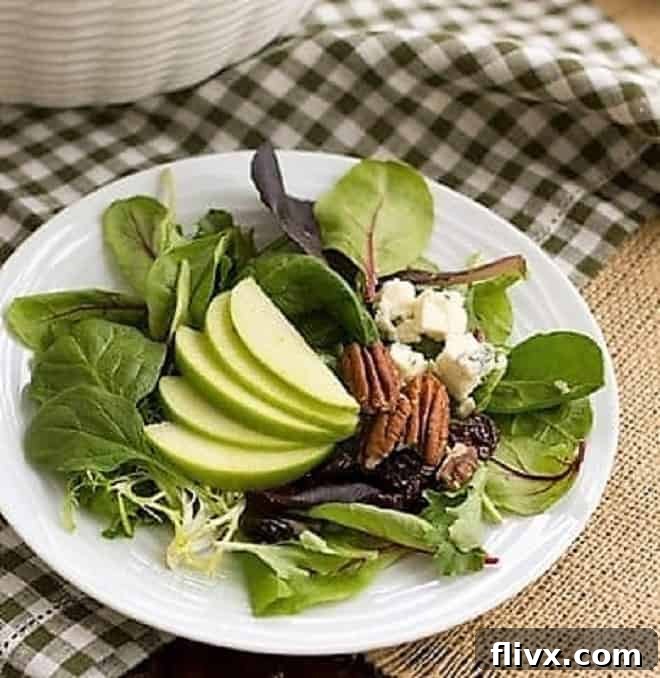 A close-up shot of the Loaded Winter Salad with Apples, Pecans, Blue Cheese and Dried Cherries served on a rustic small plate, highlighting its vibrant colors and textures.