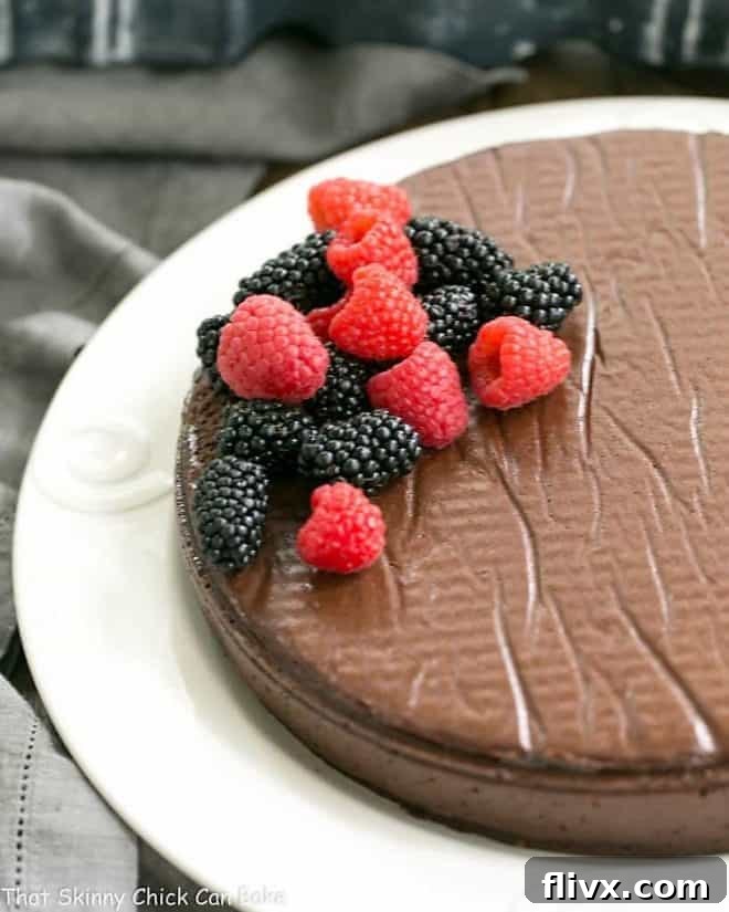 A whole Flourless Chocolate Cake, inspired by the Princeville Hotel, presented on a pristine white serving plate, elegantly garnished with a medley of fresh berries and a delicate dusting of cocoa powder.