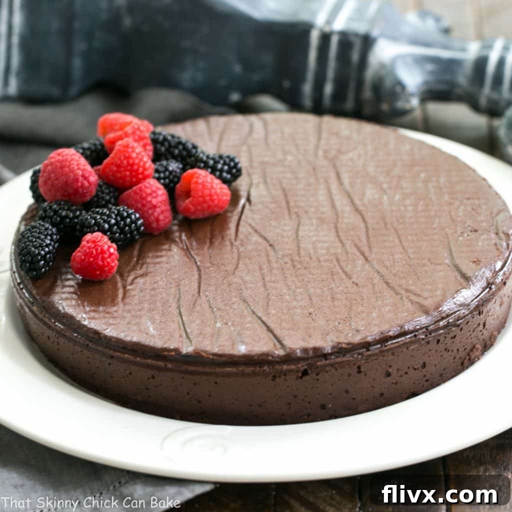 The impressive Flourless Chocolate Cake, inspired by the Princeville Hotel, proudly displayed on a white serving platter and generously garnished with a vibrant array of fresh mixed berries.