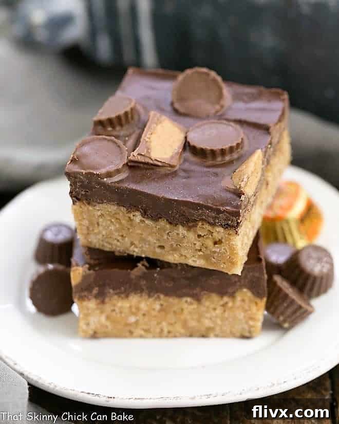 A stack of Reeses Rice Krispie Treats on a small white ceramic plate, showcasing the rich chocolate and peanut butter layers with mini Reese's cups on top.