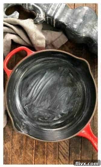 A clean cast iron skillet being greased with butter or cooking spray, ready for cookie dough.