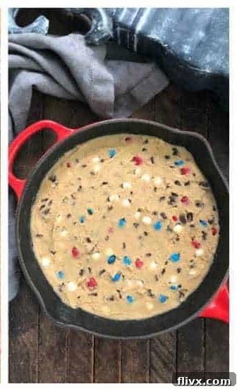 Cookie dough being spread evenly into a greased skillet with an offset spatula.