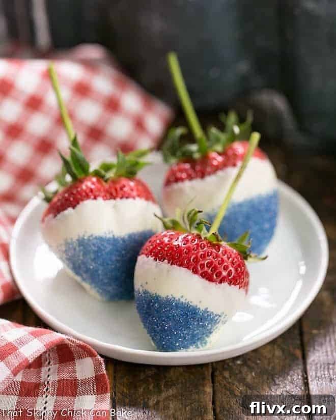 Three Red White and Blue Strawberries beautifully arranged on a small white plate, accompanied by a festive red and white checkered napkin, perfect for a patriotic celebration.