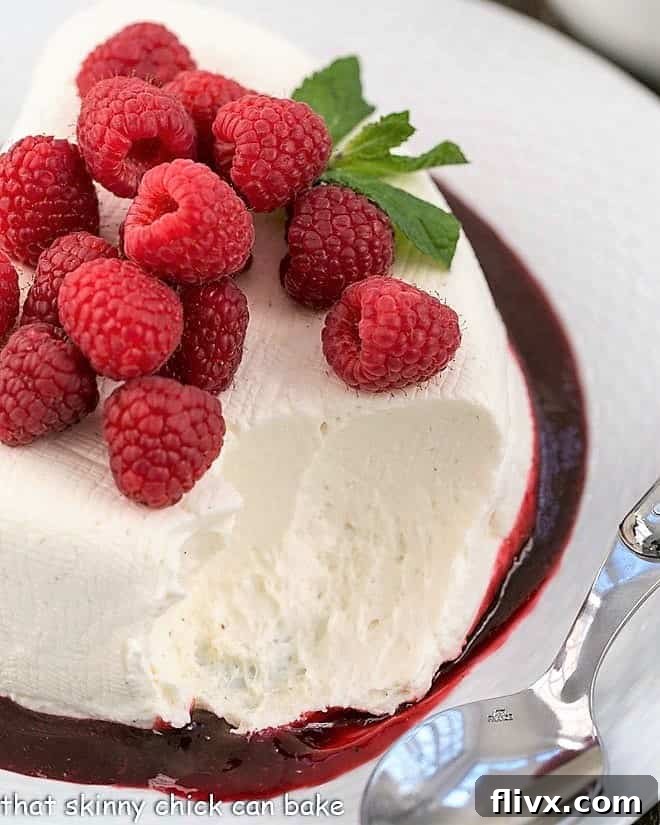 No-Bake cheesecake recipe, Coeur a la Creme, topped with fresh raspberries and a serving spoon removing a scoop.