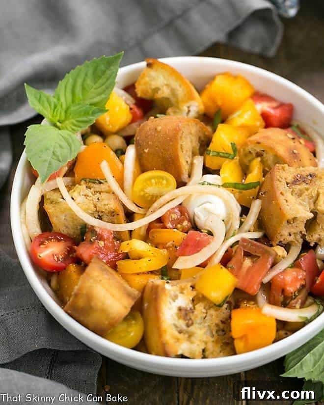 Summer Tomato and Burrata Panzanella Salad in a white serving bowl with a basil garnish.