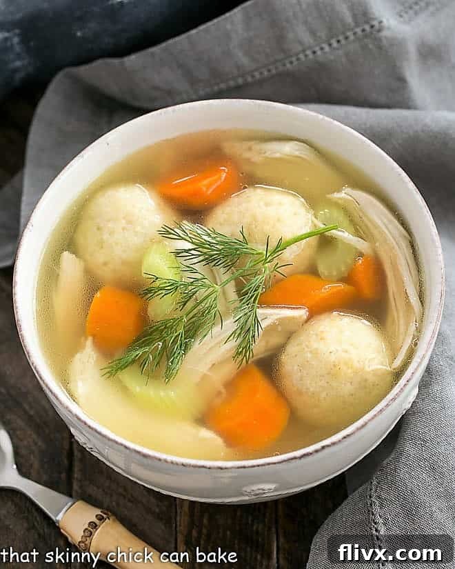 Overhead view of homemade chicken soup with fresh herbs and vegetables.