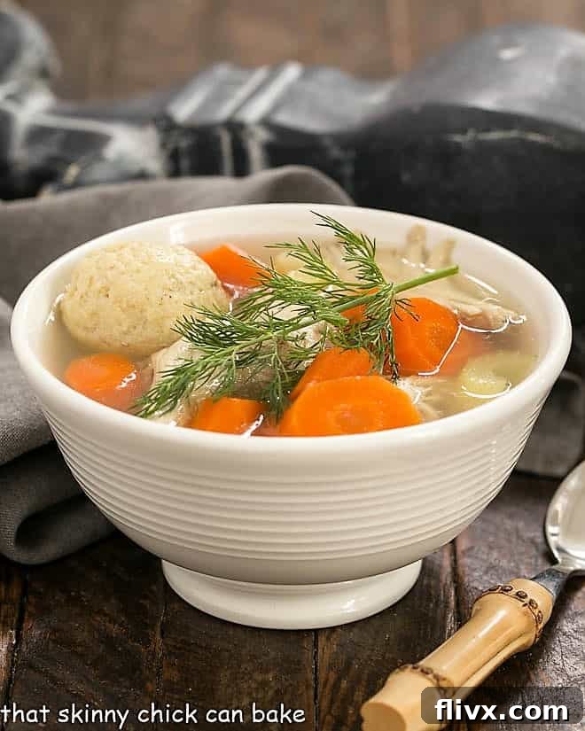 Side view of Matzo Ball soup in a white bowl with fresh dill.