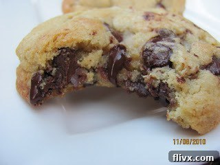 A close-up of a perfectly baked chocolate chip cookie with a bite taken out, revealing its soft, gooey center and melted chocolate.