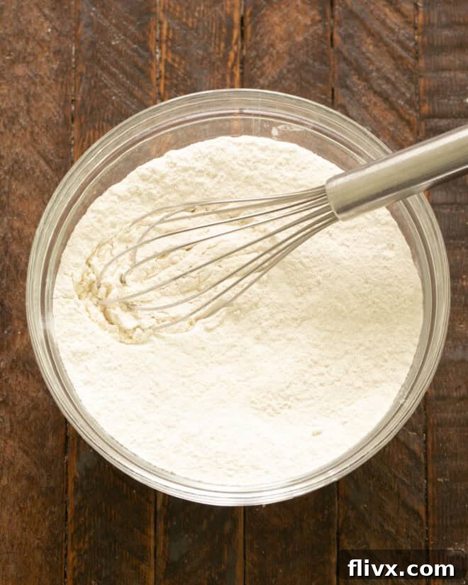 Step 1: Whisking together flour, salt, and baking soda in a mixing bowl until thoroughly combined.