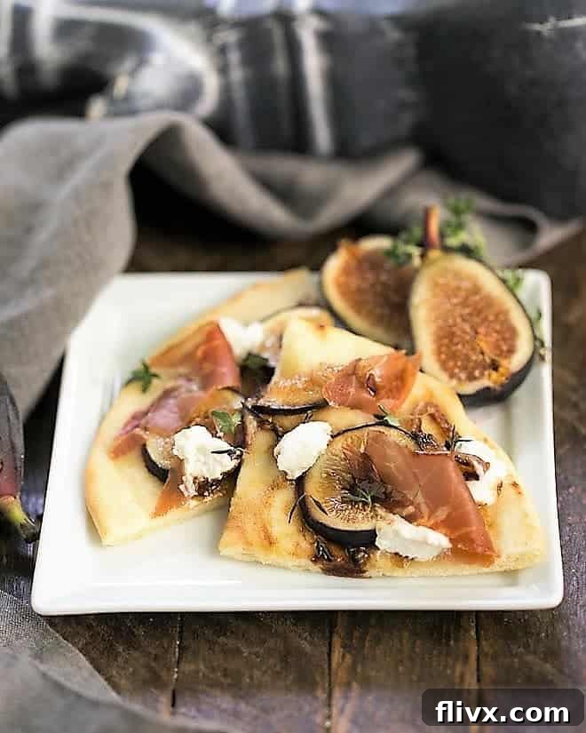 Fig, Goat Cheese and Prosciutto Pizza slices on a square white plate, garnished with fresh thyme.