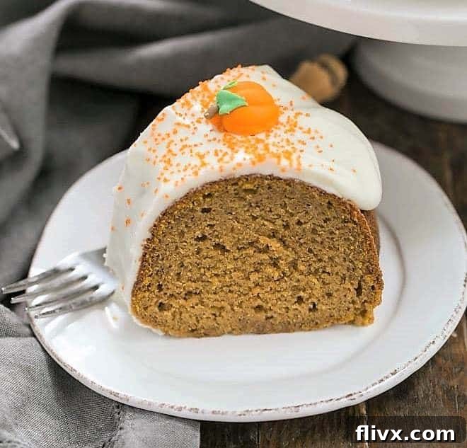 A perfectly baked slice of Pumpkin Spiced Bundt Cake on a white dessert plate, showing its moist texture and rich frosting.