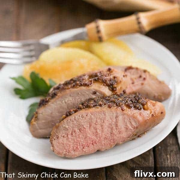 Glazed Apple Mustard Pork Tenderloin, sliced and garnished with fresh apples.