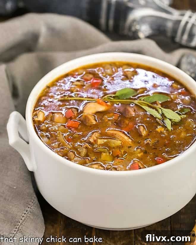 Sausage and Chicken Gumbo served in an elegant white terrine, garnished with fresh herbs