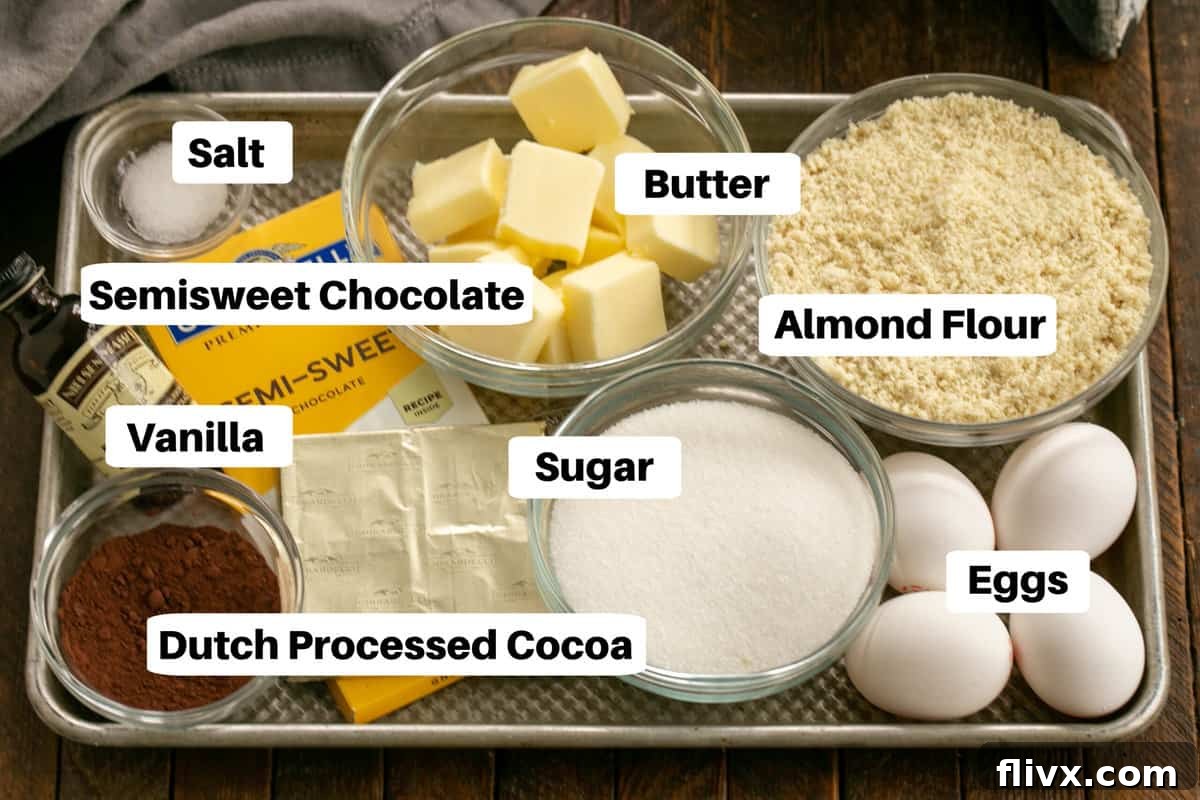 Arrangement of Torta Caprese ingredients on a sheet pan, labeled for clarity: butter, chocolate, eggs, sugar, almond flour, cocoa powder, vanilla, and salt.