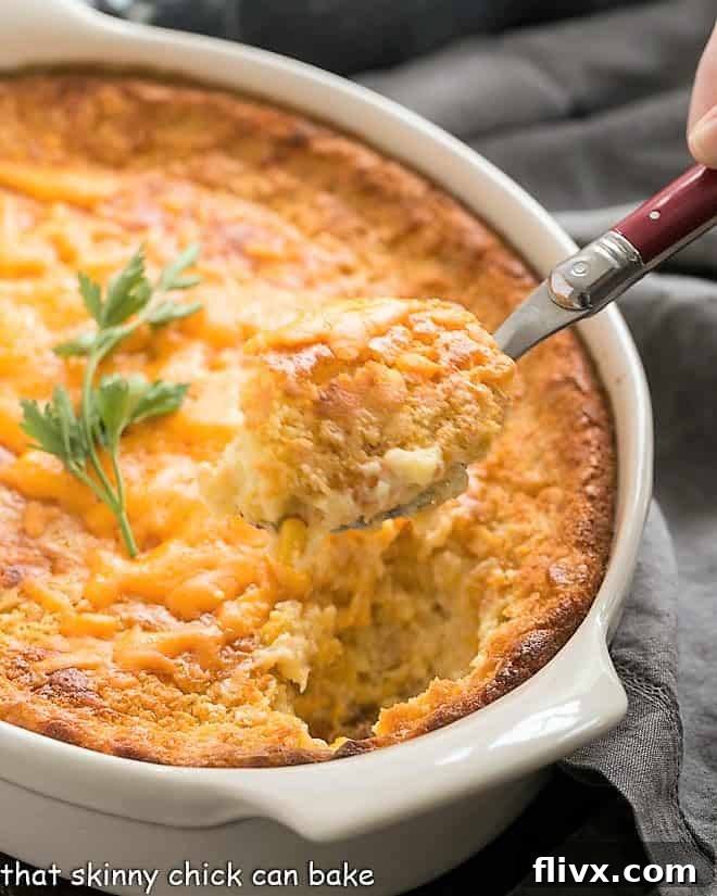 A spoonful of corn pudding recipe on a red handled serving spoon, showcasing its creamy texture.