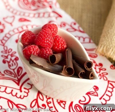 Various garnishes including fresh raspberries and mint sprigs on top of a fluffy chocolate dessert.