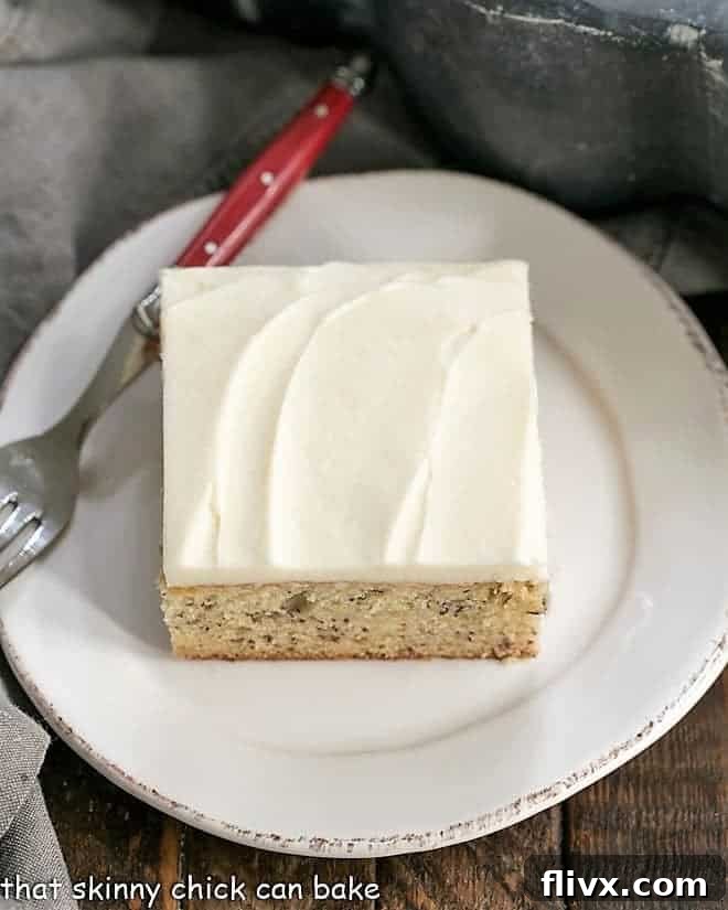 Sour Cream Banana Cake - a tender banana cake topped with a luscious layer of cream cheese frosting! Sour Cream Banana Cake on a round white plate from above, showing a perfectly sliced portion.