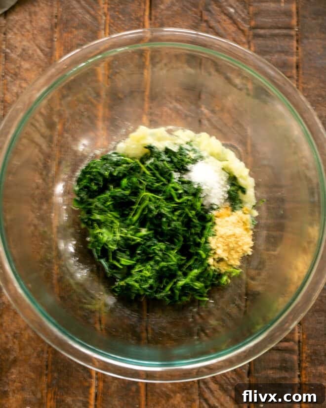 Defrosted spinach, chopped onions, and seasonings in a mixing bowl.