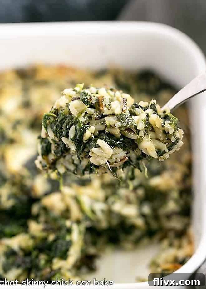A large spoonful of Cheesy Spinach Rice Casserole, showcasing its creamy and cheesy texture.